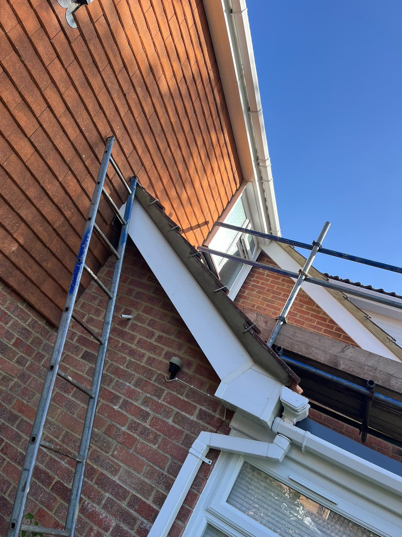 Looking up at a clipped verge where a small gable meets tile hanging